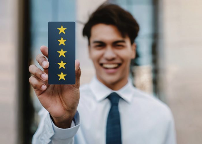 Customer Experiences Concept. Happy Young Businessman Giving Five Stars Rating and Positive Review on Card. Client's Satisfaction Surveys. Front View